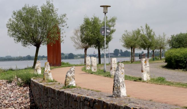 Wo das Binnenwasser einen Knick macht, steht die Skulptur Hausungen von Winnie Schaak am Ufer - im Bild leicht verdeckt von einem Bäumchen.