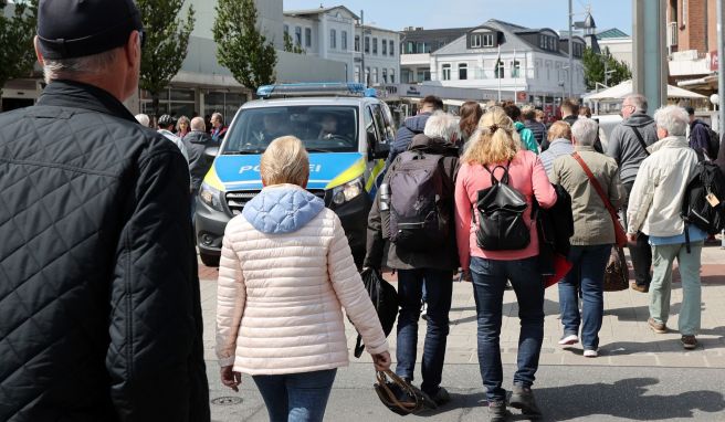 Willkommen in Westerland: Ankommende Reisende gehen am 1. Juni nahe des Bahnhofs an einem Polizeifahrzeug vorbei.