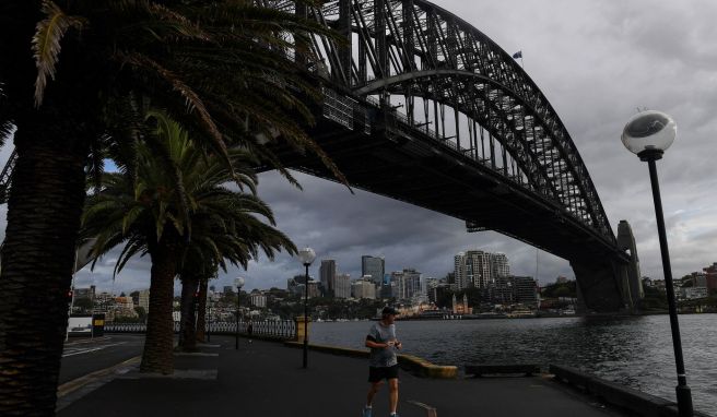 Ein Mann joggt an der Sydney Harbour Bridge vorbei. Die Sydneysider nennen ihr Wahrzeichen liebevoll den Kleiderbügel.