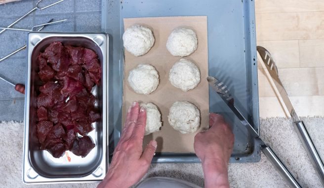 Die Rentierfleich-Stückchen werden in die fertig geformten Salzteigbällchen gedrückt.