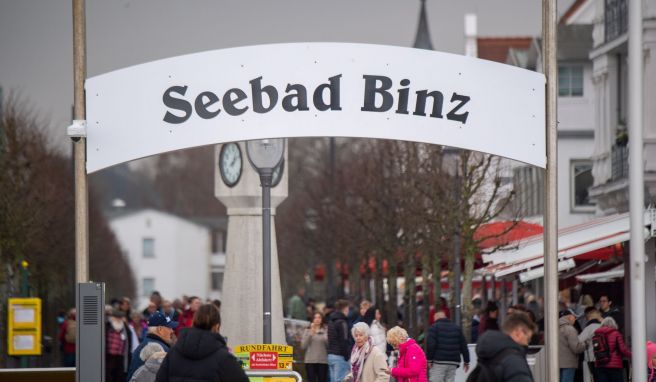 Touristen gehen im Ostseebad Binz auf der Strandpromenade entlang.