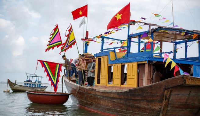 Einheimische Fischer und ältere Gläubige besteigen das Tempelboot im Rahmen des Walanbetungsfestes von Tam Hai.