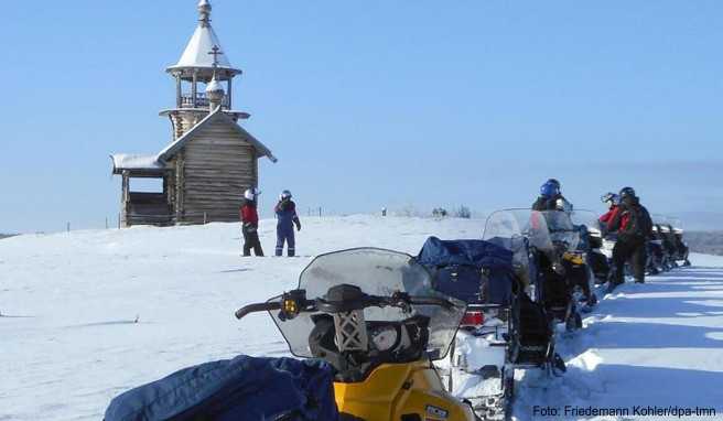 Halt am Unesco-Welterbe: Eine Gruppe von Motorschlittenfahrern macht Rast an einer der zahlreichen Holzkirchen auf der Insel Kischi im Onegasee